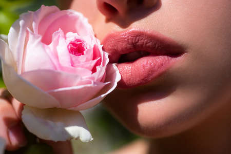 Lips closeup. Beautiful woman lips with spring rose.の写真素材