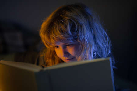 Child read fairy tale from book. Little boy in living room watching pictures in story book. Kid doing homework for elementary school. Children study.の写真素材