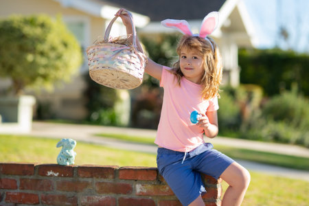 Happy Easter for children. Excited child with easter basket. Boy in bunny ears with colorful eggs...