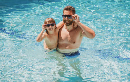 Father and son swimming in pool, summer family. Pool party. Family leisure. Summer vacation. Dad and...