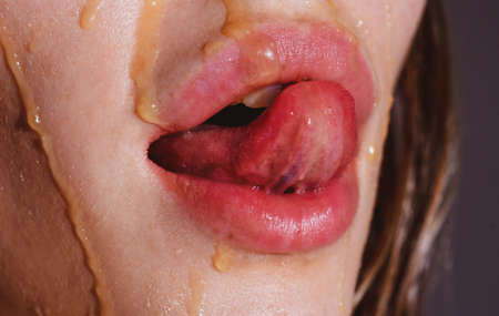 Honey. Sweet, sexy lips. Sweet taste on the female mouth. Lips in honey. Gloss of lips and womans mouth. Sensual lips. Tongue mouth biting lip.の写真素材