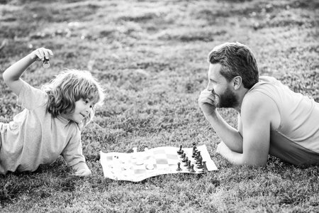 Father and son playing chess spending time together in park.の写真素材