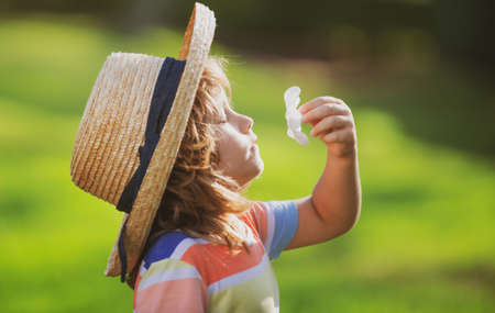 Caucasian child portrait close up. Kids in straw hat smelling plumeria flower on summer nature park.の写真素材