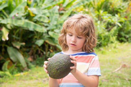 Cute boy hold avocado, close up portrait on nature background.の写真素材