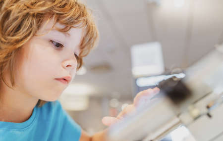 Child chooses in gadget store. Smart digital technics. Kid in computer shop. Digital equipment. Gadget sale.の写真素材