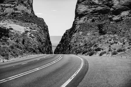 A long straight road leading towards a rocky mountain.