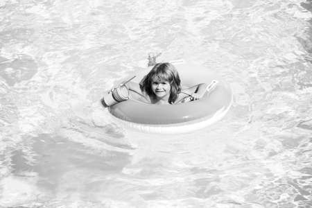 Kid with colorful floating ring. Child in swimming pool. Summer holiday. Kids water toys. Little boy swim. Child water toys. Children play in tropical resort. Family beach vacation.の写真素材