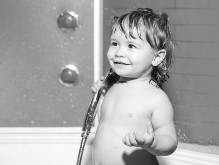Cute child playing in bathtube. Funny happy baby bathes in bathtub with water and foam. Kids hygiene.の写真素材