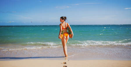Sexy woman in swimsuits bikini hold pineapple near butt, buttocks on summer beach.