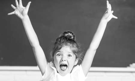 Excited school girl face with surprising expression against blackboard.の写真素材