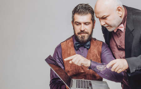 Adult education. Handsome caucasian man teaching senior dad or grandfather how to use laptop or notebook.の写真素材