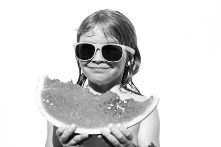 Child boy eats watermelon near the pool. Kid with water melon, isolated on white. Kids summer activities.の写真素材