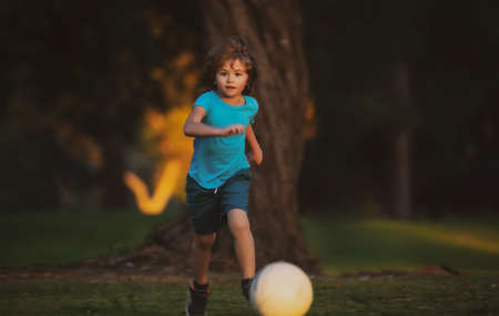 Boy football player kicking football on the sports field. Active kids. Child soccer. Young sporty kids.の写真素材