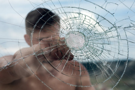 Fist punch. Ready to fight. Man boxing cracked glass, strength and power. Criminal guy with serious face.の写真素材