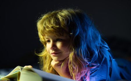 Closeup portrait of hild reading book. Little boy read books in living room watching pictures in...