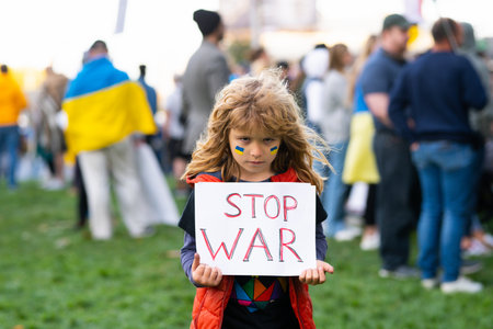 Young kid holding a poster with Stop war message, activism and human rights movement, outdoor lifestyle. Child carries a sign Stop war. Russian geopolitics and crisis in Ukraine.の写真素材