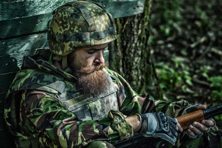 Tired soldier. Army soldier with assault rifle and combat helmet. Battle of the military in the war. Military soldier or officer with weapons.の写真素材