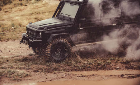 Off road jeep expedition to the villages on mountain road. Classic 4x4 car crossing water with splashes on muddy road. Off road car.の写真素材