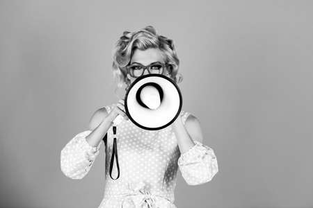 Speaking loudly in the megaphone. Beauty woman with megaphone isolated on pink.の写真素材