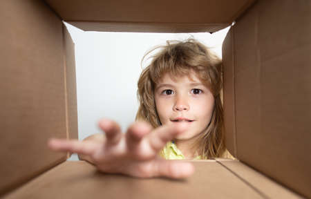 Cheerful cute child opening a present. View from inside of the box. Parcels and delivery.の写真素材