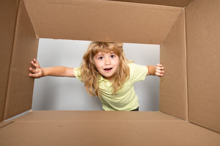 Cheerful cute child opening a present. Cardboard boxes, parcels. Delivery service concept. Children...
