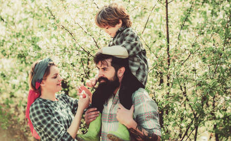 Happy family in garden. Lifestyle and family life. Small boy with father and mother in orchard in...