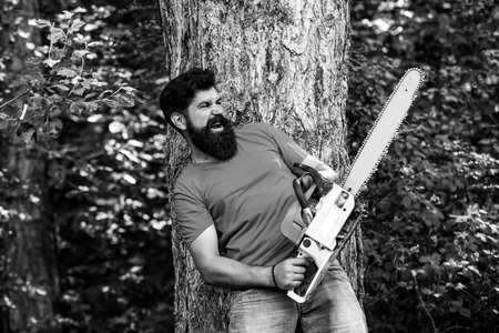 Lumberjack with chainsaw on forest background. Man doing mans job. Lumberjack with chainsaw in his hands. Lumberjack concept. Firewood as a renewable energy source.の写真素材
