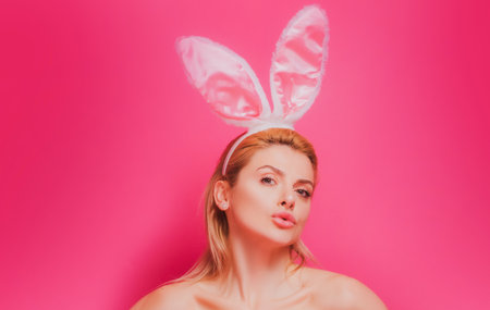 Lovely beautiful sensual young woman posing in pink bunny ears. Studio shot of easter girl isolated on pink.の写真素材