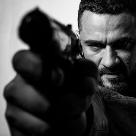 Need for revenge. Close up gun barrel. Killer or murderer concept. Head hunting. Man handsome mafia killer going to shot someone. Finish him. Kill them all. Final shot. Concentrate on gun shotの写真素材