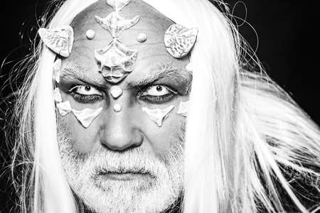 Elderly man holding two red horns. Burning diabolic demon summons evil forces and opens hell. Evil...