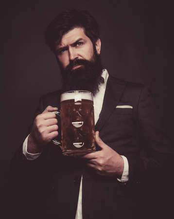 Happy elegant man drinking beer. Senior man in black suit drinking beer with surprise face.の写真素材