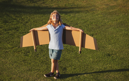 Child boy playing and dreaming about summer vacation and travel. Kids imagination and freedom concept. Little boy dream of flying, traveling on plane, fantasies.の写真素材
