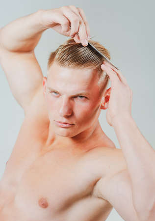 Man hairstyle hairdresser. Guy with comb. Beauty, grooming and people concept. Handsome male brushing hair with comb. Isolated.の写真素材