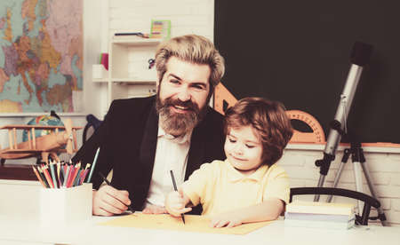 Cute little preschool kid boy with teacher study in a classroom. Teacher and pupil in classroom.の写真素材