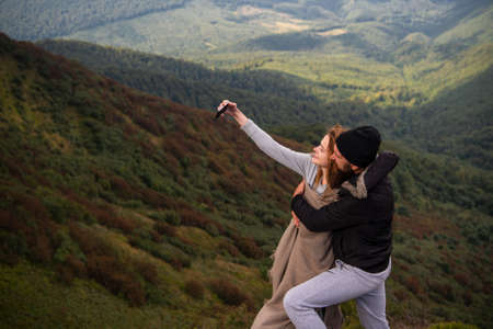 Couple shooting selfie on near forest background. Nature and lifestyle concept. Romantic lovers at countryside camping.の写真素材