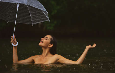Naked girl with umbrella. Raining, flood. Autumn time.