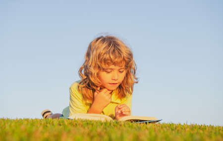 Kids imagination, innovation and inspiration children. Outdoor portrait of little boy reading a book.の写真素材