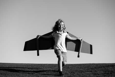 Child boy playing with toy airplane wings. Kids dream of becoming a pilot. Superhero flying.