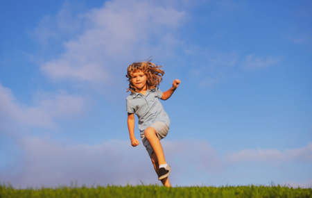 Happy child having fun outdoors. Kid playing in summer park. Little boy running on green fresh grass...