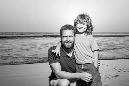 Father and son hugging on beach sunset. Little son embrace daddy on a sea sunrise.の写真素材