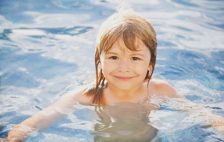 Happy boy playing and in swimming pool or sea water. Funny kids summer face.