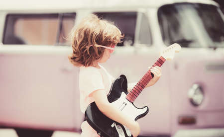 Playing guitar make a living. Portrait of cute kid boy at guitar practice.