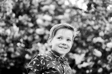 Smiling child happy boy in pink blooming japanese sakura background. Springtime bloom blossom.の写真素材