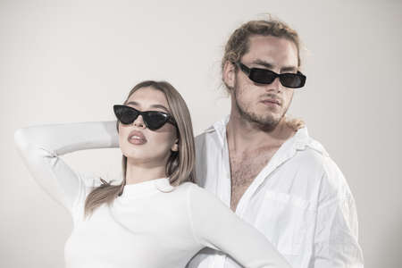 Couple in fashion black sunglasses. Young couple posing with sunglasses. Studio shot on gray background.の写真素材