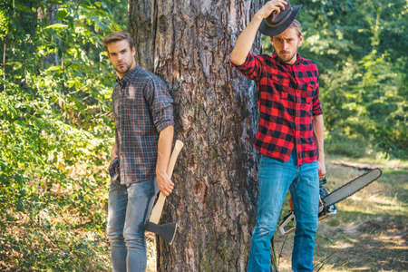 Man with axe in forest. Lumberjack woodcutter in a plaid shirt. Lumberjack brutal bearded man in red checkered shirt.の写真素材
