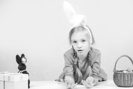 Cute girl in bunny ears on Easter day. Girl holding painted eggs.の写真素材