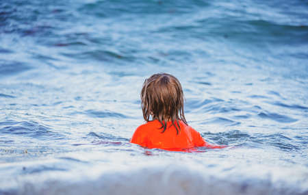 Happy child playing in the sea. Little boy swimming on Waves at sea. Kid having fun and jumping in the waves of the sea.の写真素材