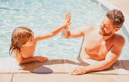Father and son swimming in pool, summer family. Child with dad playing in swimmingpool. Family time. Summer vacation. Pool party.の写真素材