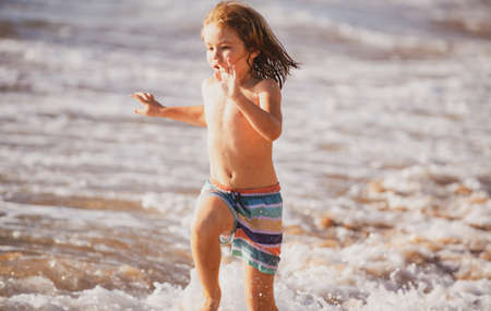 Kid running on beach. Happy child run in sea on summer vacation. Travel and adventure on sea or ocean.の写真素材