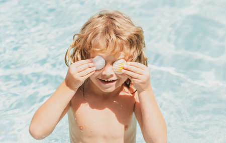 Happy child having fun at swimming pool on summer day. Children playing in blue sea water. Tropical summer vacation concept. Happy sunny day on the beach of tropical island. Family holiday.の写真素材